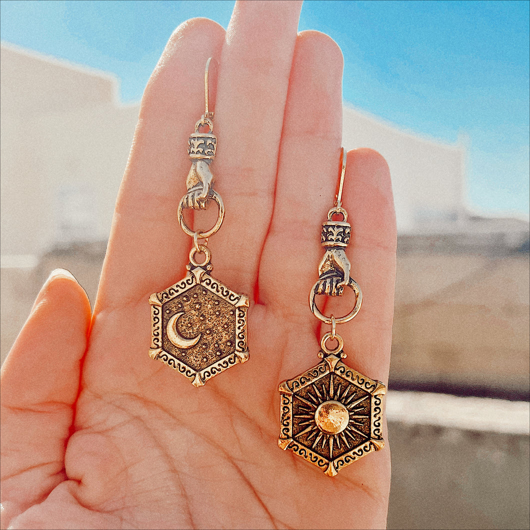 Hands holding Sun and Moon Earrings 🐍